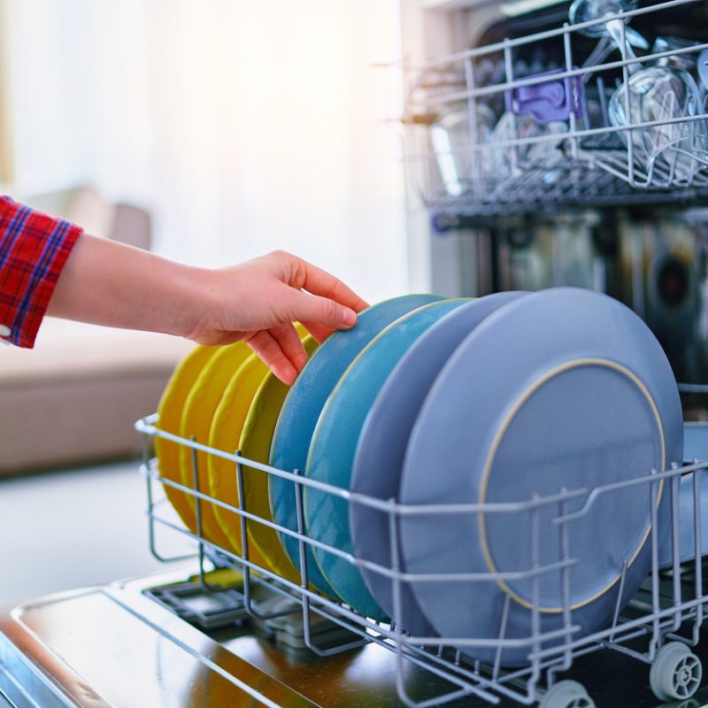 Housewife woman using modern dishwasher for wash dishes at home kitchen